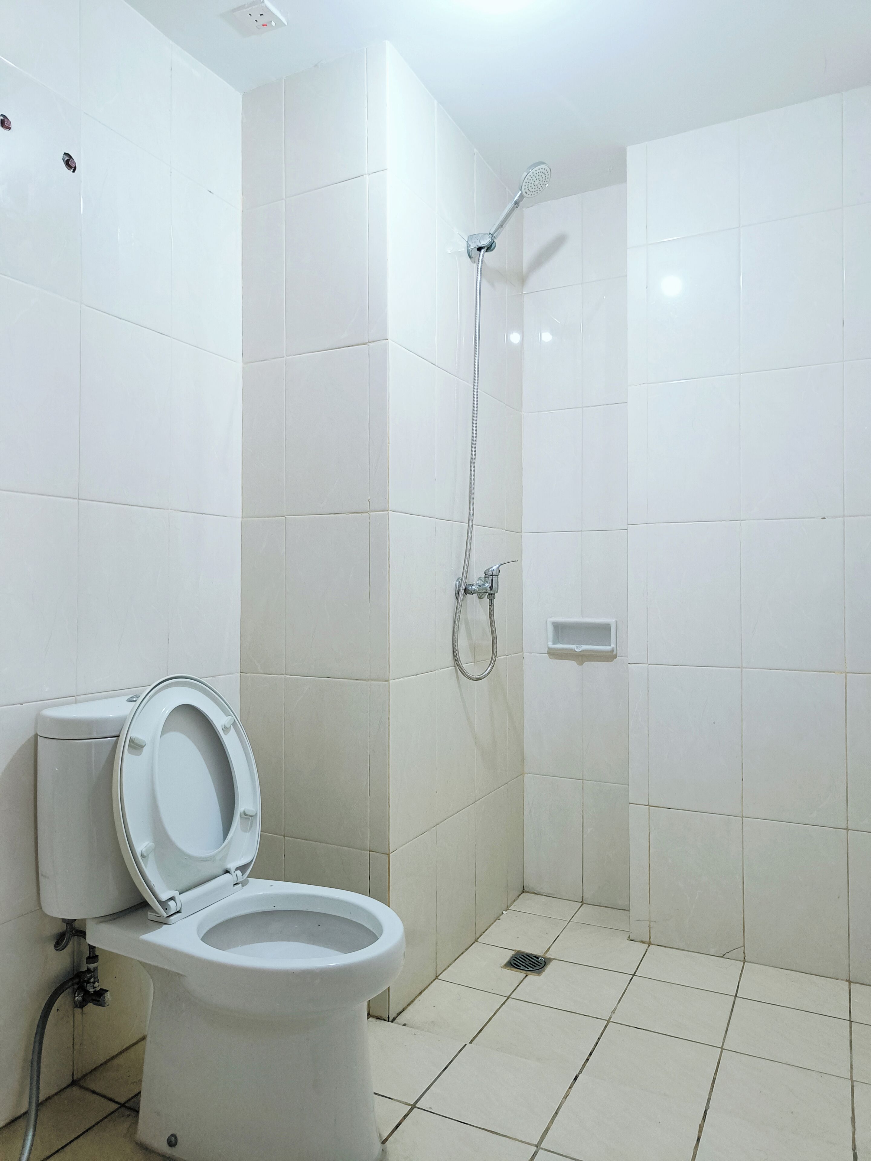Une salle de bain avec des toilettes, une douche et des murs carrelés.