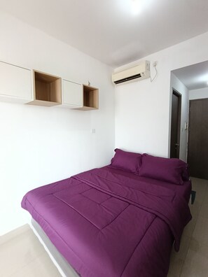 A bedroom with a bed, built-in shelves, an air conditioning unit, and a door. - Apartemen The Archies by Linkara (Jakarta)