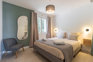 A bedroom with a bed, a chair, a mirror, a window with curtains, and a bedside lamp. - Mas de l'Etoile - Exceptional villa in Provence (Mimet)