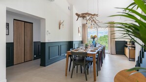 Un espace repas avec une longue table, des chaises et une vue par la fenêtre.