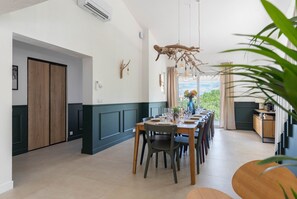 A dining area with a long table, chairs, and a view through the window. - Mas de l'Etoile - Exceptional villa in Provence (Mimet)