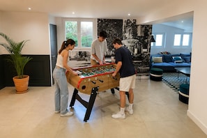 A modern living room with a foosball table, a sofa, and a potted plant. - Mas de l'Etoile - Exceptional villa in Provence (Mimet)