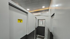 En modern hisschakt med en skylt som visar ”Hisskorg nr 3” och ett ”Tvättrum” med en tryckknapp.