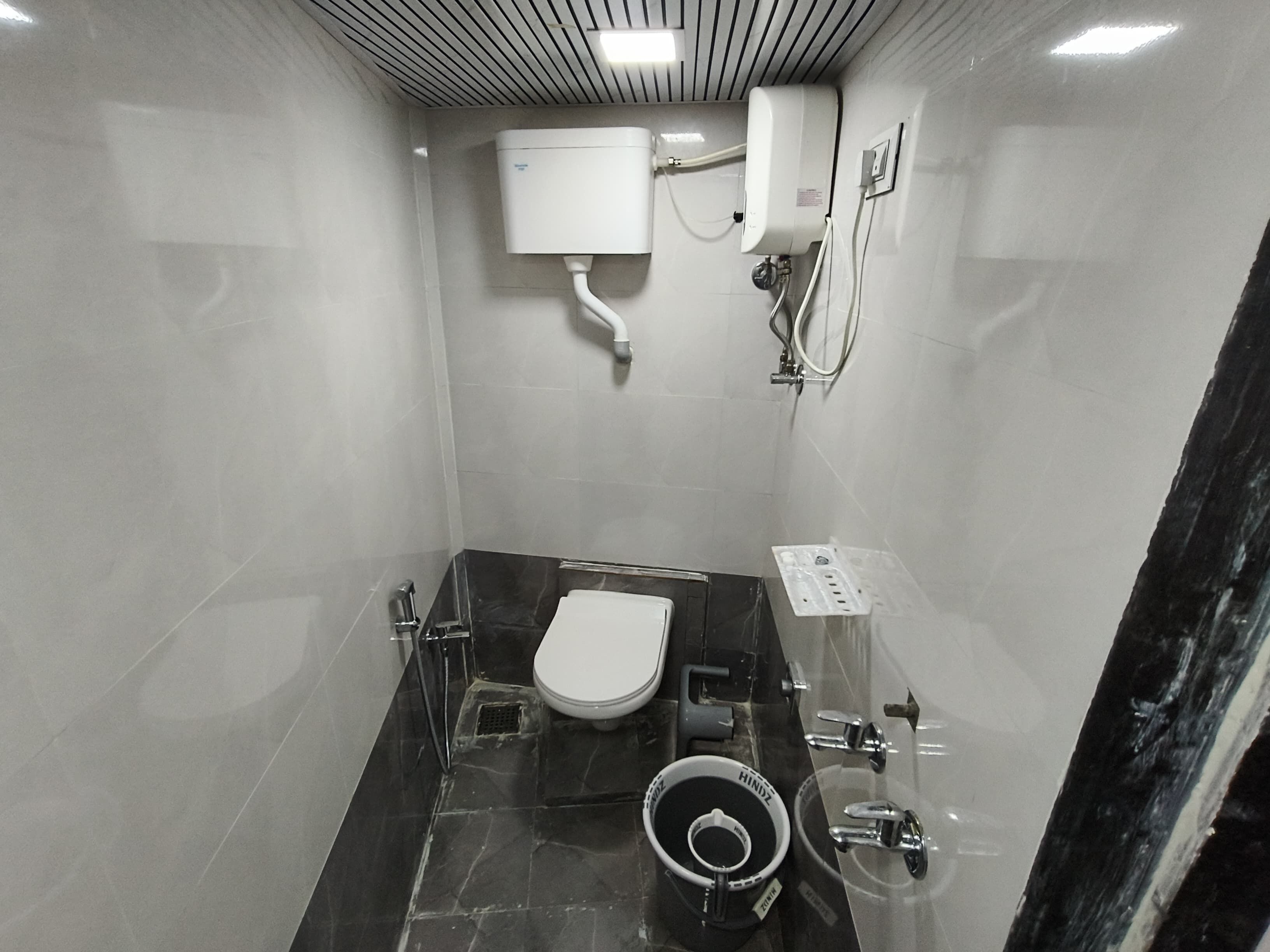 A compact bathroom with a toilet, bidet, and a hand dryer.