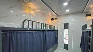 Ett modernt hotellrum med en våningssäng, ett badrum med en spegel och en dörr som leder till ett annat rum.