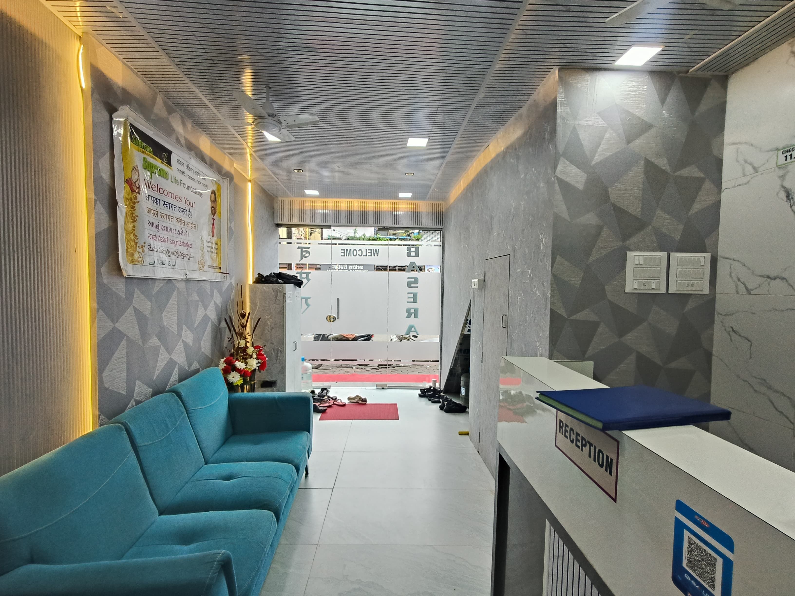 A reception area with a blue sofa, a reception desk, and a wall with geometric patterns.