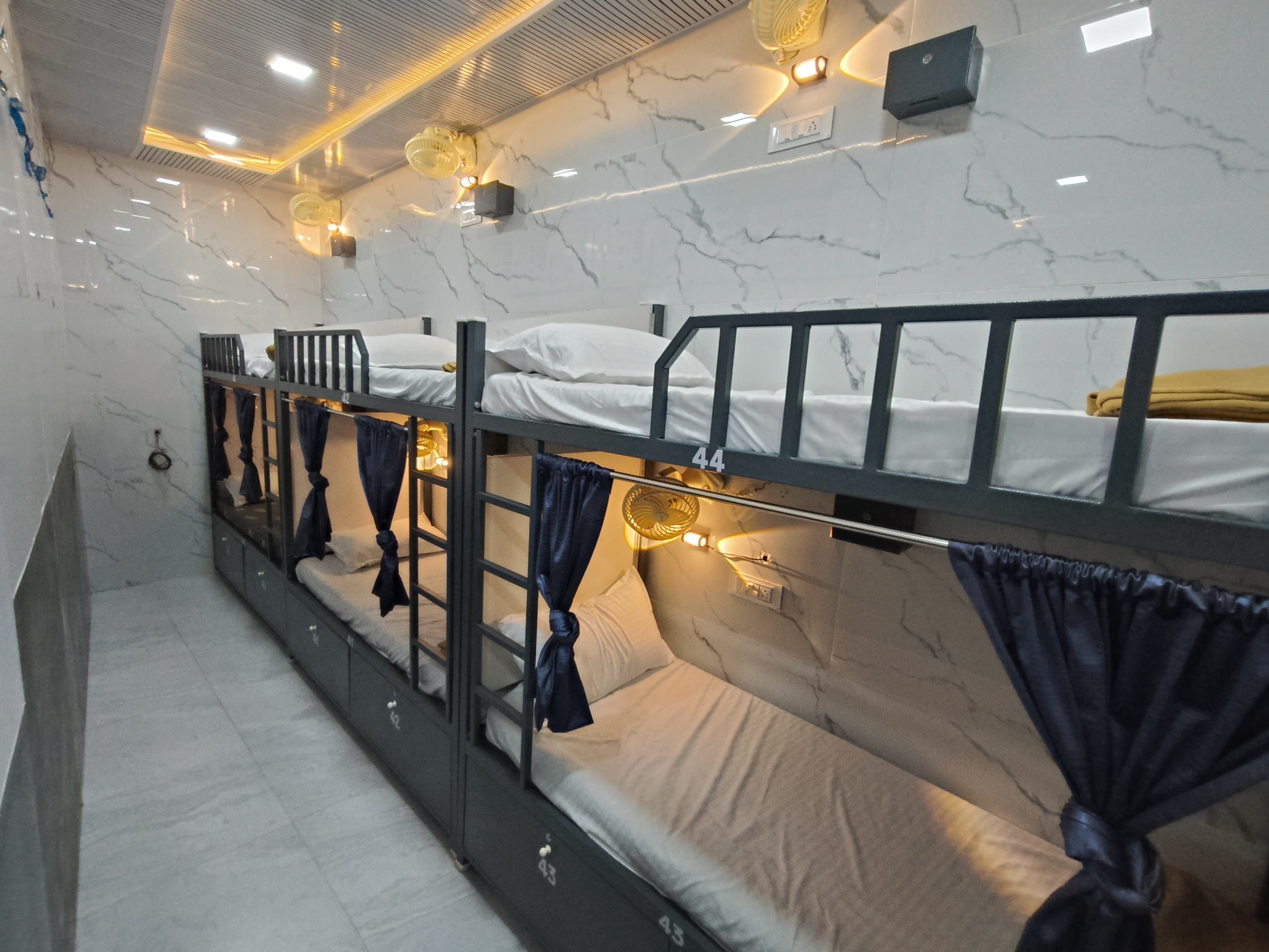 A bunk bed room with marble walls, built-in lighting, and curtains.