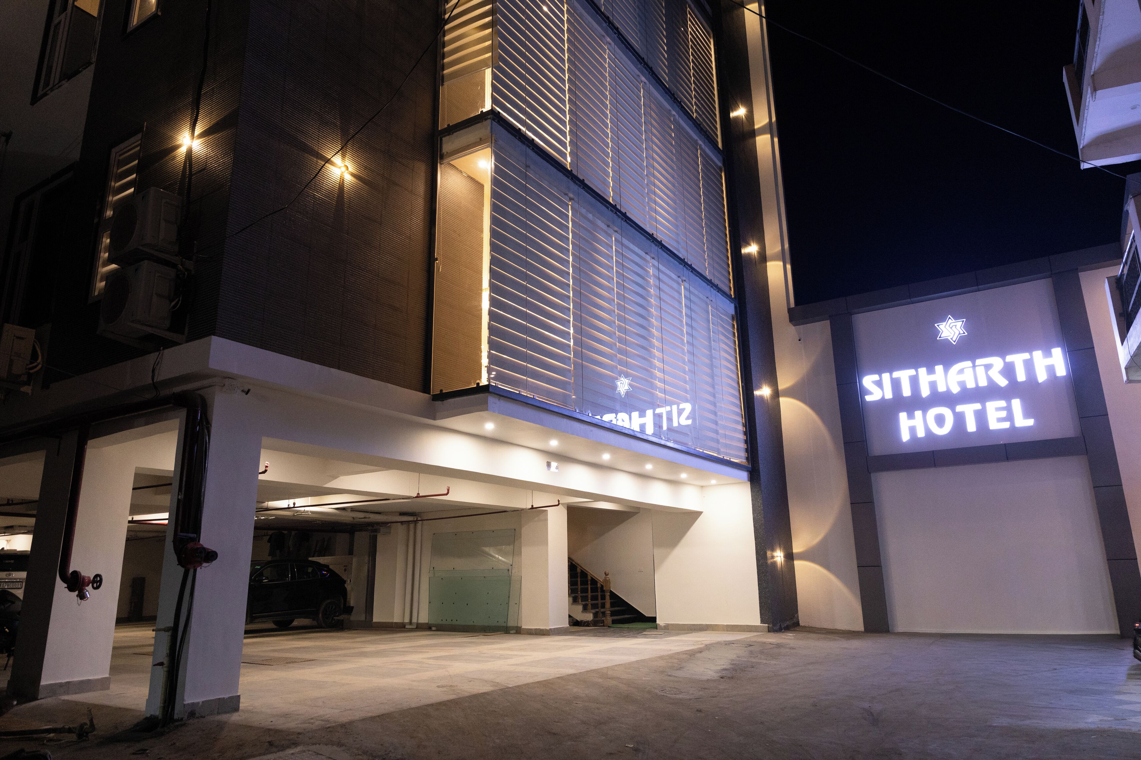 A modern hotel with a prominent sign reading "SITHARTH HOTEL" and a visible staircase leading to the entrance.