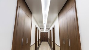 A long, narrow hallway with wooden doors on both sides and a tiled floor. - Sitharth Hotel (Vikasnagar)