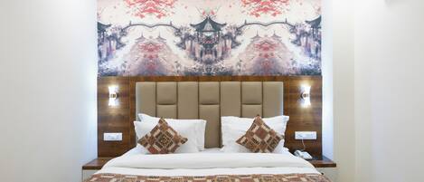 Una cama bien hecha con una colcha estampada, un cabecero de madera y dos almohadas decorativas.