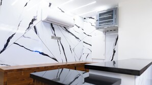 A reception desk with a marble wall, wooden paneling, and a mounted television. - Sitharth Hotel (Vikasnagar)