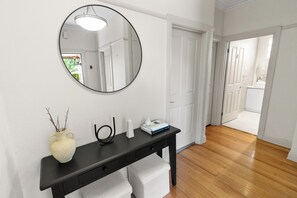 Een moderne badkamer met een zwart wastafelmeubel, witte handdoeken, een ronde spiegel en een vaas met takken.