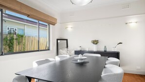 Ein modernes Esszimmer mit einem dunklen Holztisch, grau gepolsterten Stühlen und Blick auf einen Holzzaun.