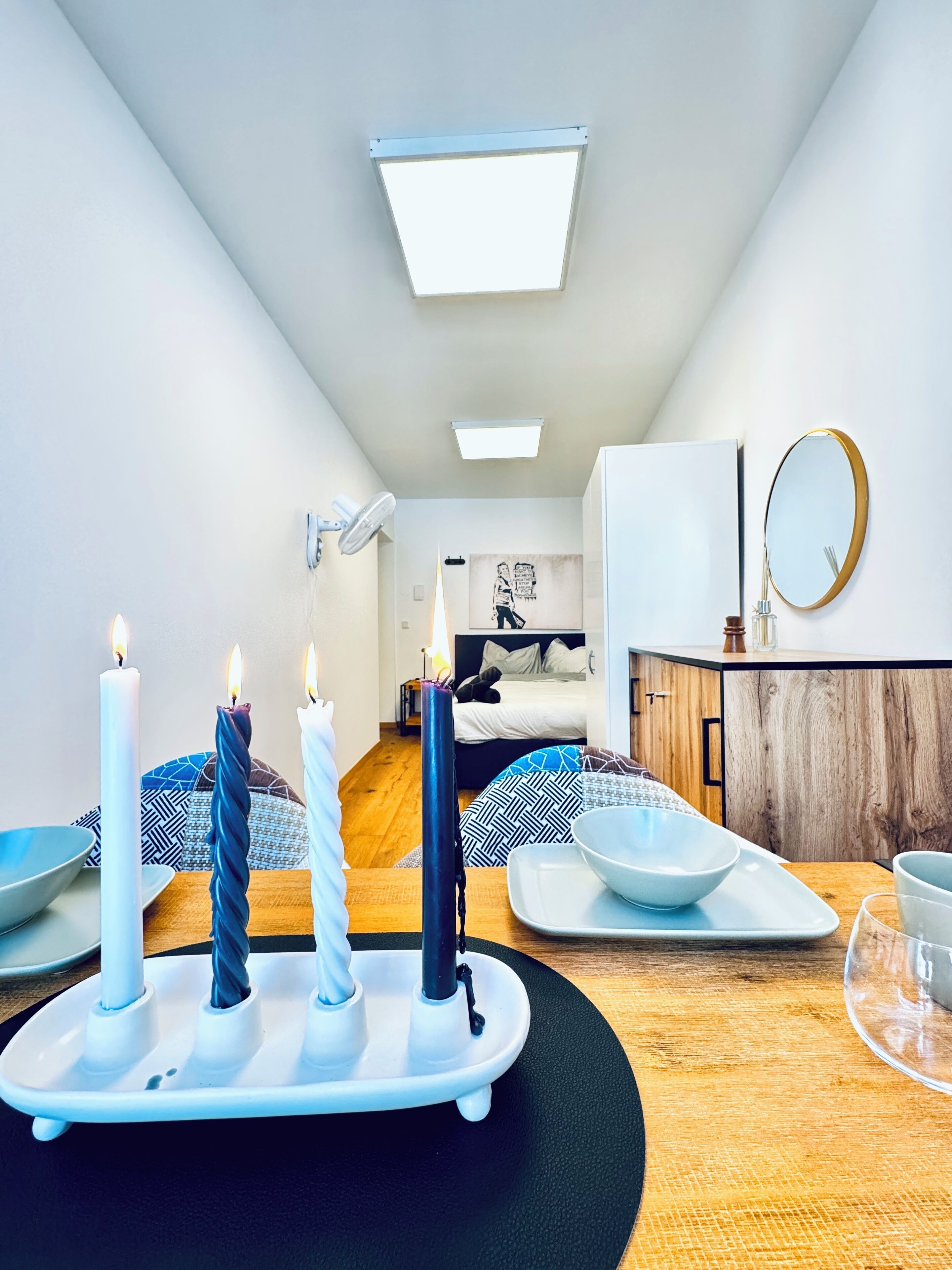 Una habitación moderna y bien iluminada con una cama, una mesita de noche y un espejo en la pared.
