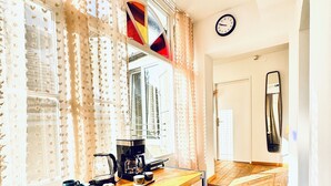 A kitchen with a wooden countertop, a coffee maker, and a kettle. There is a window with curtains and a mirror on the wall. - Comfortable Room Near Kaufpark Alterlaa (Vienna)