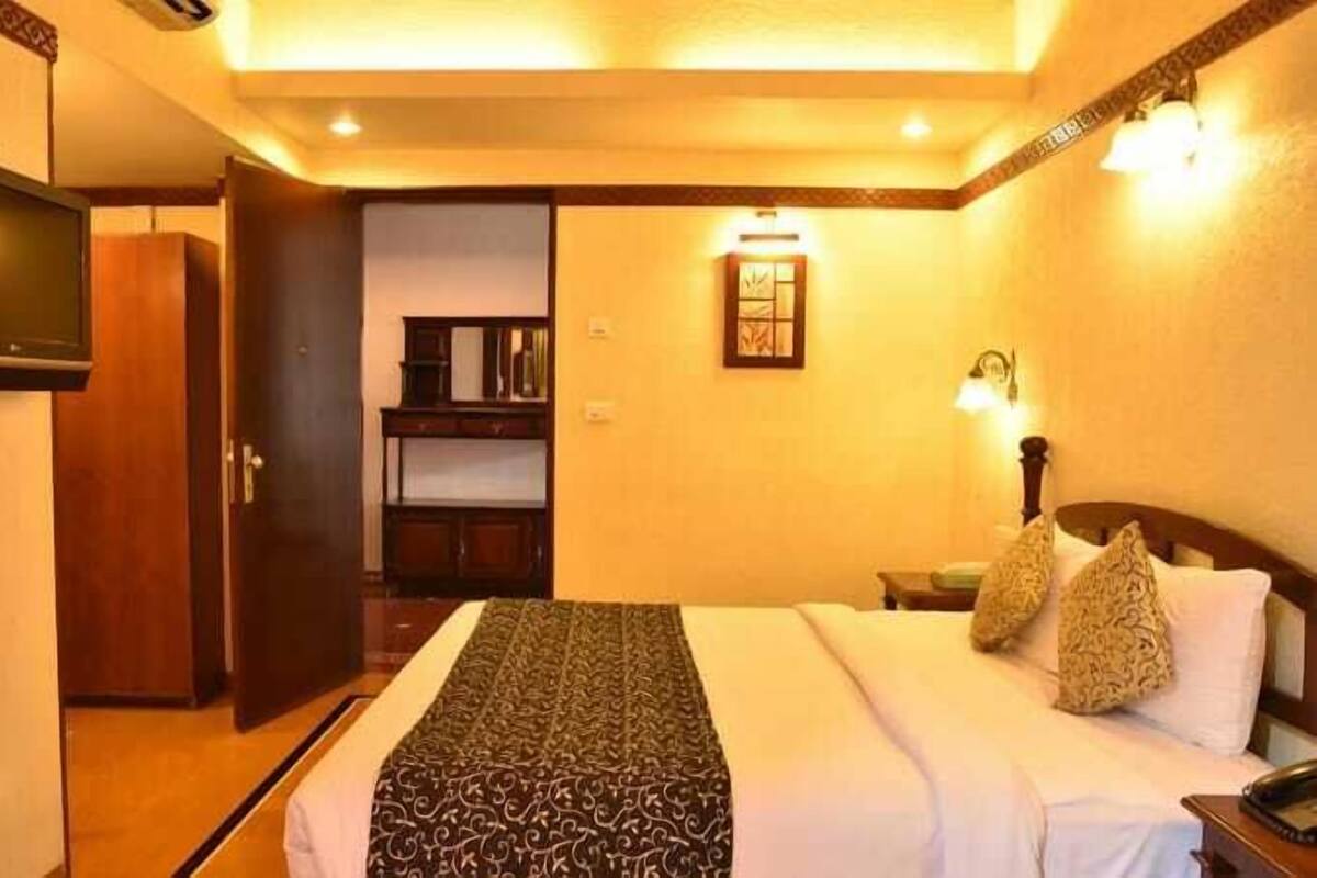 Una habitación de hotel con cama, televisor, escritorio y armario.