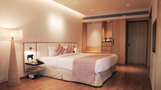 A hotel room with a bed, bedside table, lamp, and wardrobe. - Hotel Shiv Shakti  (Rajkot)