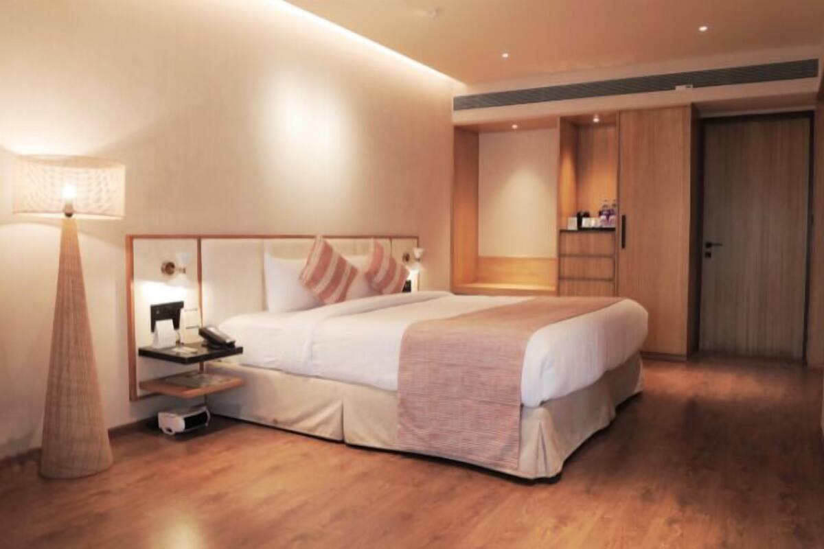Una habitación de hotel con cama, mesita de noche, lámpara y armario.