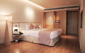 A hotel room with a bed, bedside table, lamp, and wardrobe. - Hotel Shiv Shakti  (Rajkot)
