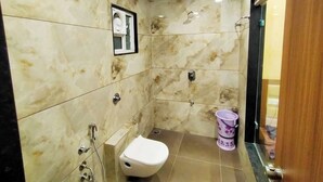 A small bathroom with a toilet, a shower, and a sink. - Hotel Shiv Shakti  (Rajkot)