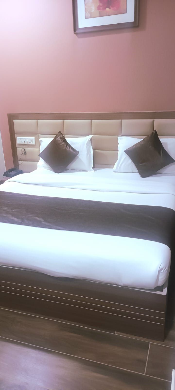 Una cama con cabecera, dos almohadas y una colcha.