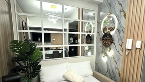 Ein Hotelzimmer mit Bett, einer Zimmerpflanze, einem Schreibtisch und einem großen Fenster mit Blick ins Zimmerinnere.