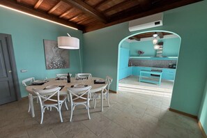 A dining area with a round table, white chairs, and a pendant light.