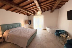 A bedroom with a bed, a bathtub, a chair, and a table.