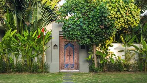 A traditional building with a decorative door, surrounded by lush greenery and a well-maintained lawn. - Exclusive 5-Bedroom Luxury Villa in Canggu, Walking Distance to the Beach! (Tanggu)