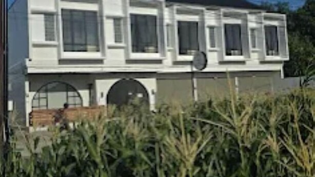 Un bâtiment à deux étages, doté d’une façade symétrique, de grandes fenêtres et d’un toit plat.