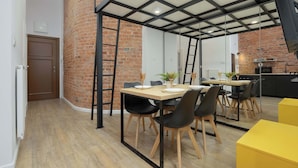 Uma área de refeições com parede de tijolos, piso de madeira e design moderno no teto.