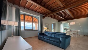 A living room with a sofa, a table, and a view of the outdoors. - Inviting apartment in Poppi with patio (Poppi)