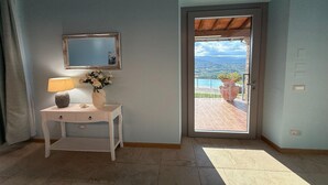 A room with a desk, a lamp, a vase with flowers, a mirror, and a door leading to an outdoor area with a view. - Inviting apartment in Poppi with patio (Poppi)