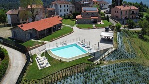 A residential area with a swimming pool, stone buildings, and a mountainous backdrop. - Inviting apartment in Poppi with patio (Poppi)