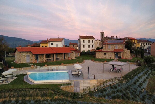 A residential area with a swimming pool, outdoor seating, and a view of the surrounding landscape. - Spacious apartment with infinity pool (Poppi)