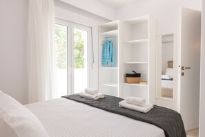 A modern hotel room with a large bed, a wardrobe with hanging space, and a window with curtains. - Sky, Luxury Apartment (Rhodes)