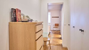 Un couloir avec un meuble en bois, une chaise en verre et une porte donnant sur une autre pièce.