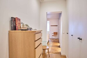 Ein Flur mit einem Holzschrank, einem Glastischstuhl und einer Tür zu einem weiteren Raum.