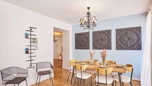 Un espace repas doté d’un parquet en bois disposé en motif de chevron, d’un lustre et de trois panneaux décoratifs fixés au mur.