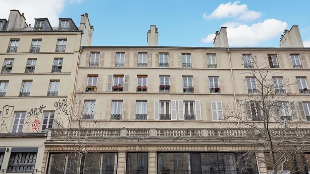 Une rangée d’immeubles à plusieurs étages, dotés de balcons et de grandes fenêtres, avec un ciel dégagé.