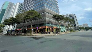 A tall, modern skyscraper with a reflective glass facade, surrounded by other high-rise buildings and a few trees. - Victory Tower (Ho Chi Minh City)