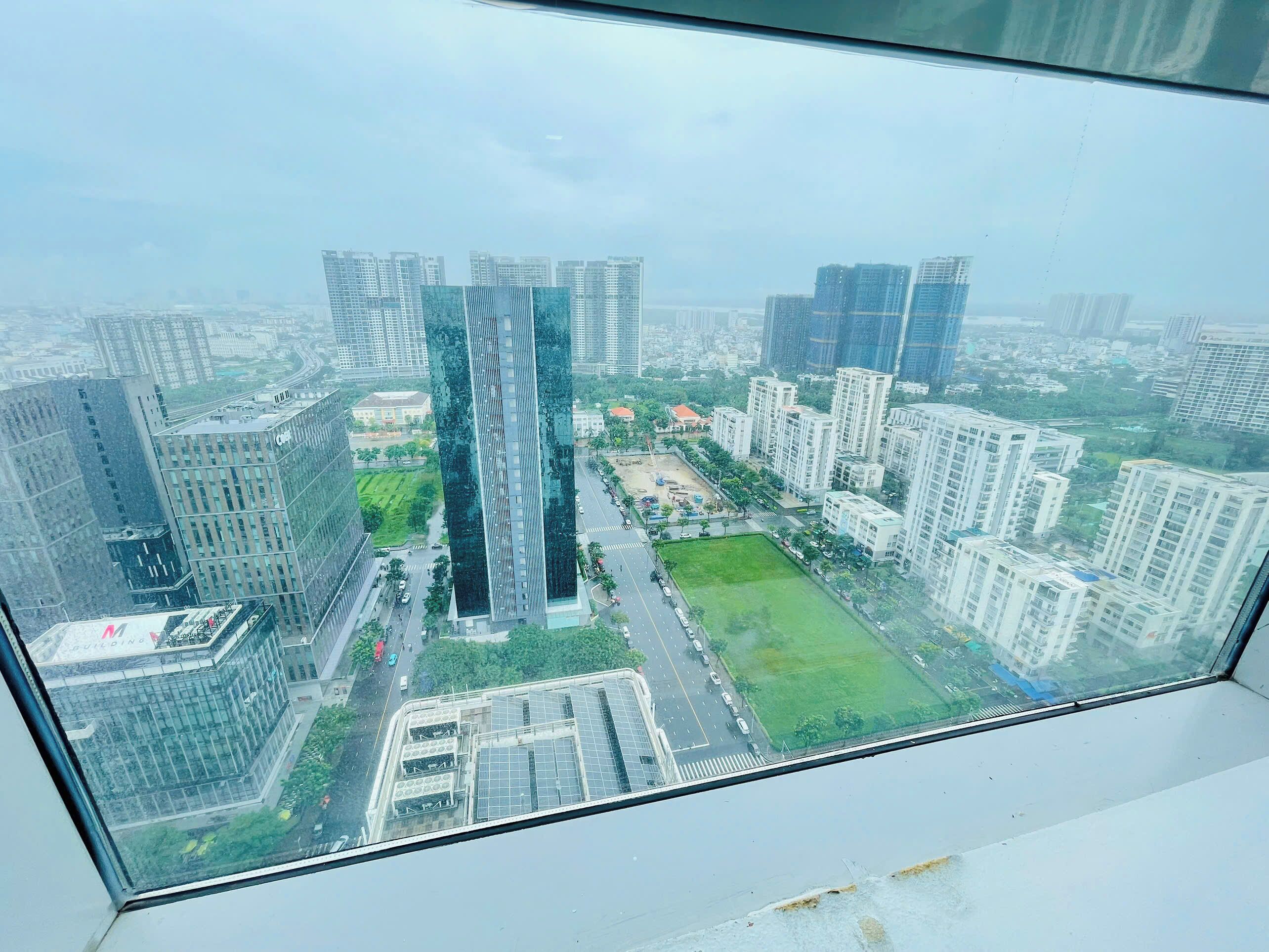 A high-rise building with a modern glass facade, surrounded by other high-rise buildings and a green park area.