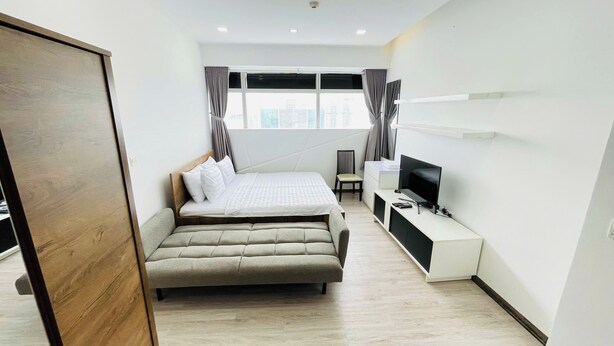 Une chambre d’hôtel moderne, dotée d’un grand lit, d’une télévision, d’un bureau et d’une fenêtre avec des rideaux.