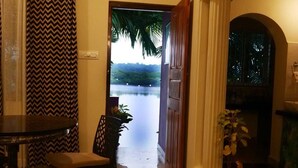 Une pièce avec vue sur un plan d’eau, une porte en bois, une table avec des chaises et un rideau à motifs.