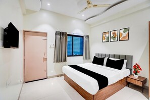 A modern bedroom with a large bed, a ceiling fan, a window with curtains, and framed artwork on the wall. - Collection O Shendra Midc Aurangabad (Chhatrapati Sambhajinagar)