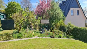 A residential house with a well-maintained garden, a small gazebo, and a clear blue sky. - Romantischer Rückzugsort in Kröpelin in Strandnähe (Kröpelin)