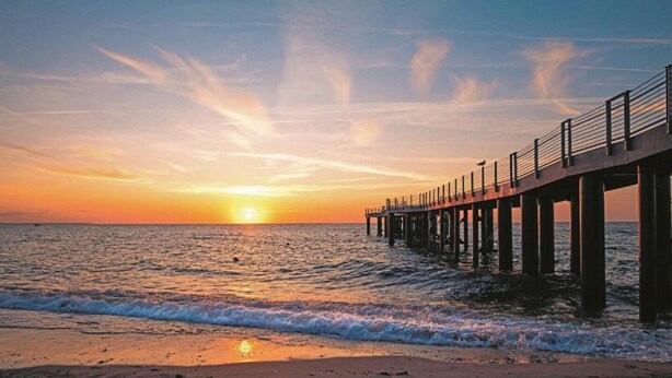A pier extending into the ocean at sunset with the sun visible near the horizon. - Romantischer Rückzugsort in Kröpelin in Strandnähe (Kröpelin)