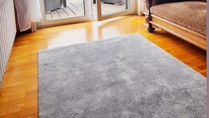 A room with a sliding glass door leading to an outdoor deck, a grey rug, a wooden floor, a brown sofa, and a chandelier. - Romantischer Rückzugsort in Kröpelin in Strandnähe (Kröpelin)