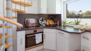 Uma cozinha compacta com forno embutido, pia e escada de madeira.