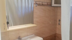 Ein Badezimmer mit Waschbecken, Spiegel, Toilette und Duschvorhang.